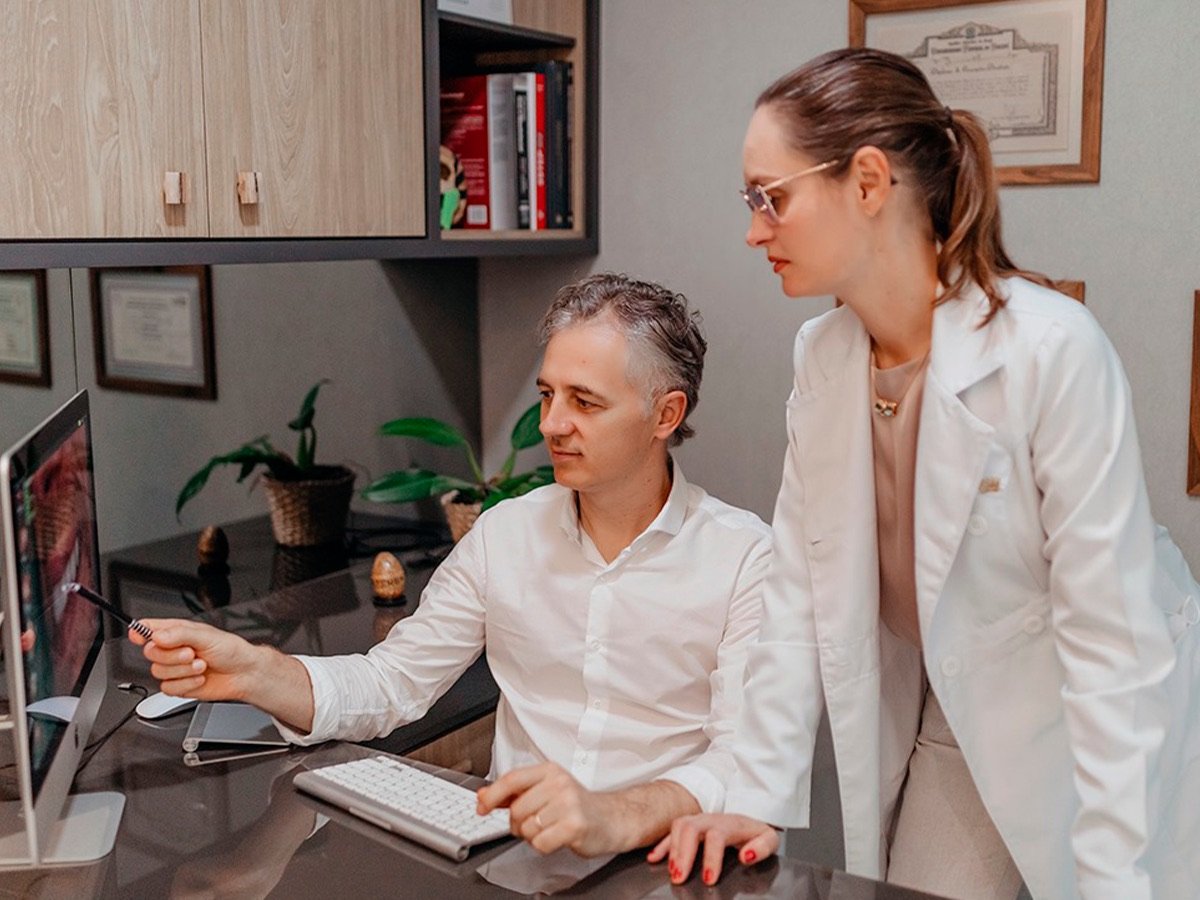 Dr. Roberto e Dra. Michelle analisando exames de imagem no computador da clínica